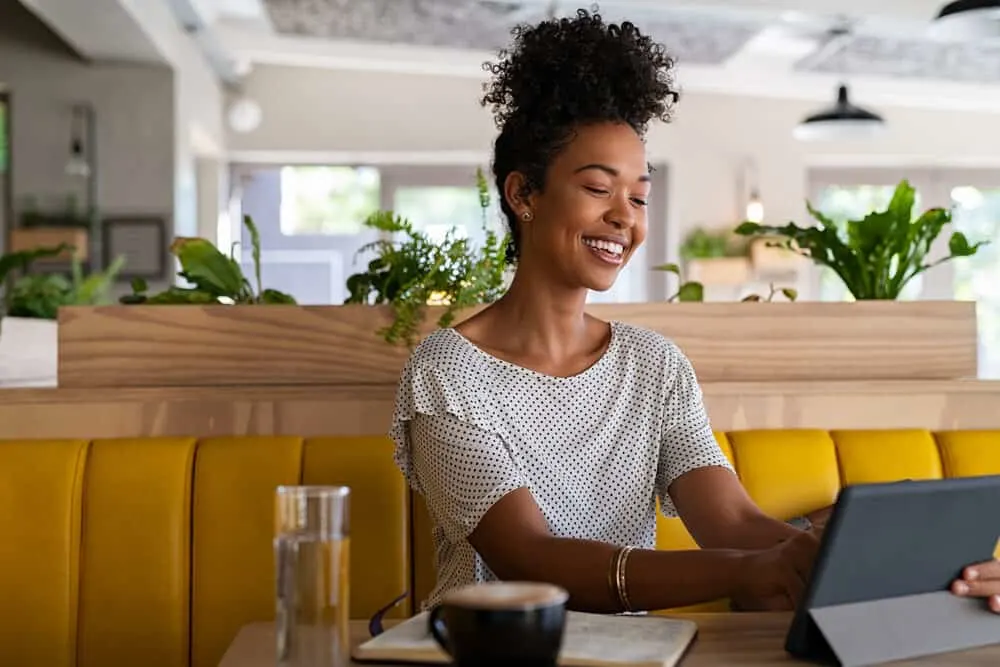 Black lady researching the anti-inflammatory properties and antioxidant properties of applying jojoba oil to your hair.