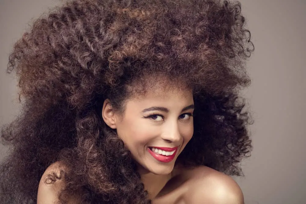 Beautiful black female wearing red lipstick and a synthetic wig under a wig cap covering her own hair.