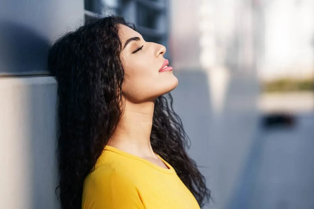 A young mixed-raced woman with a straight hair texture created loose waves with sea salt spray.