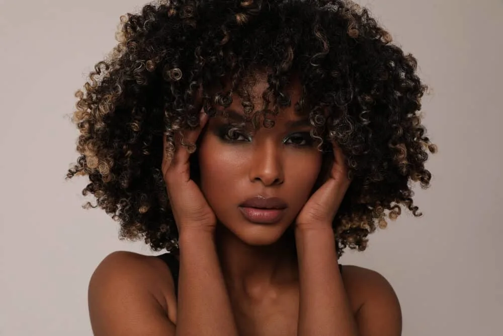 Lady with curly black and brown greasy hair due to product buildup.