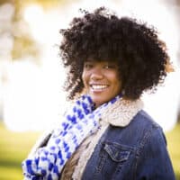 African American woman with thinning hair wearing an artificial hair wig covering her own hair.