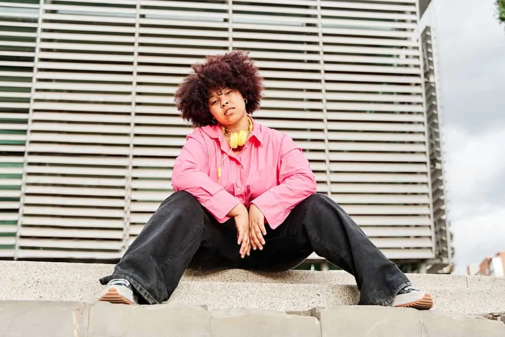 Young African lady with big beautiful natural curls with red low lights covering her naturally dark hair.