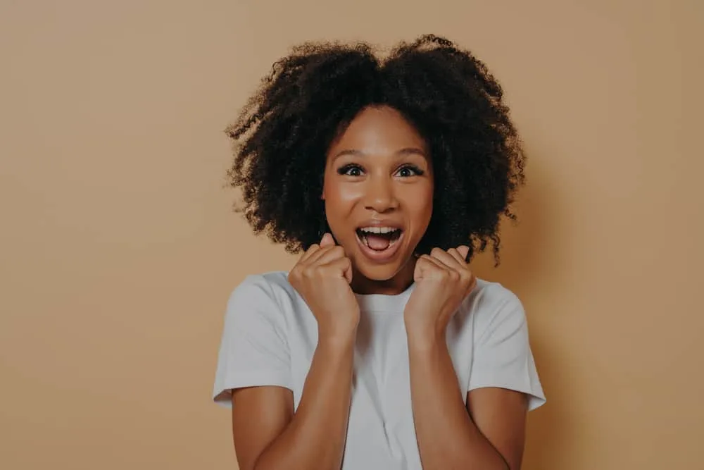 Amazed young woman with curly frizzy hair that prevents her hair from seeming as long since it's not a straight look.