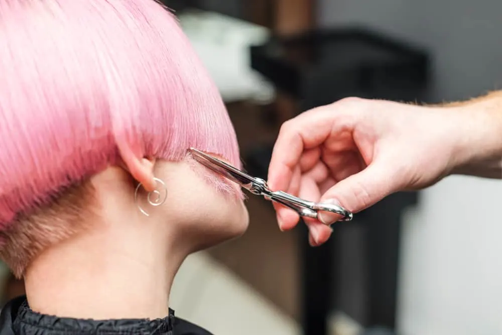 Stylist in a full-service salon providing an adult haircut after a clarifying shampoo and subtle ombre hair coloring.