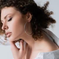 White girl with very curly hair that's a mixture of dark brown and blond hair in a kinky natural afro hairstyle.