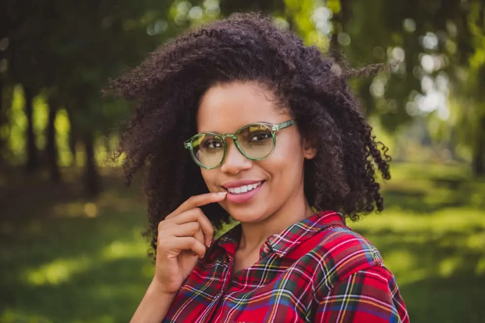 African female with thin hair has a curly wolf hair cut on her kinky dry hair.