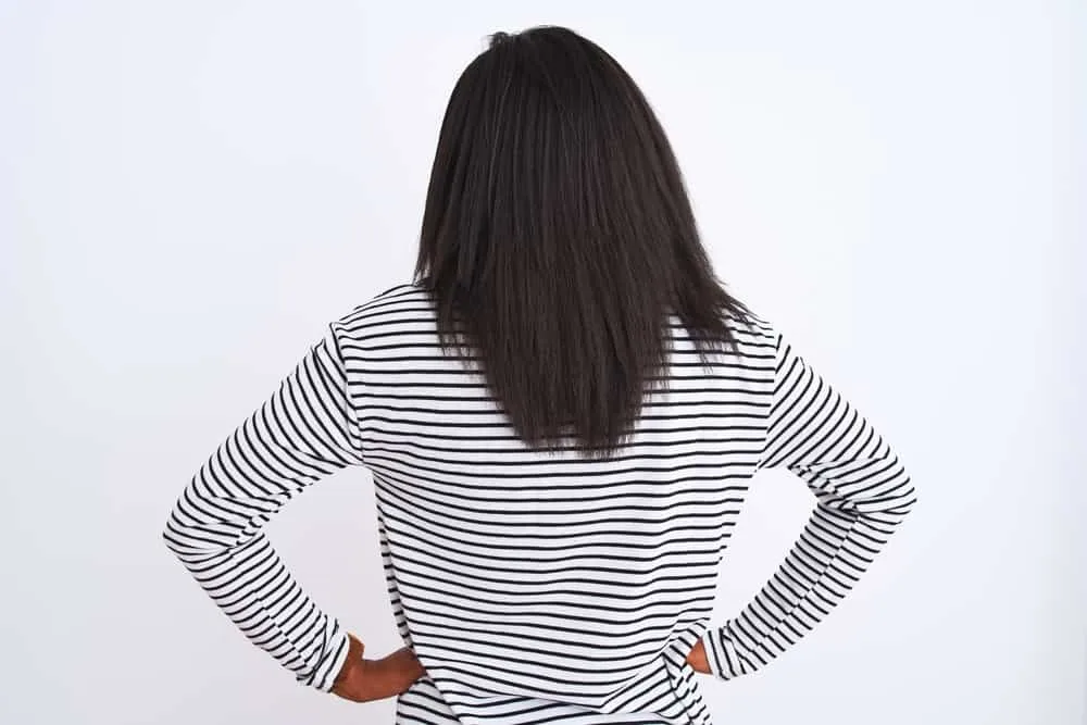 A black lady with type 4A hair shows the results of her hair care routine that has grown her hair.