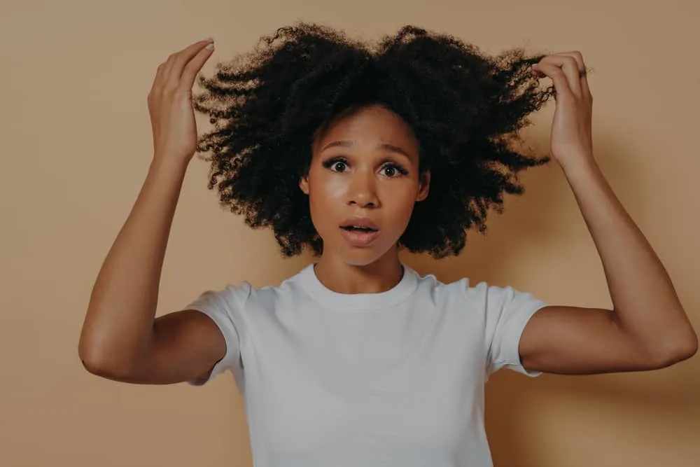 A lady with shoulder-length frizzy hair wearing her curls in their natural state.