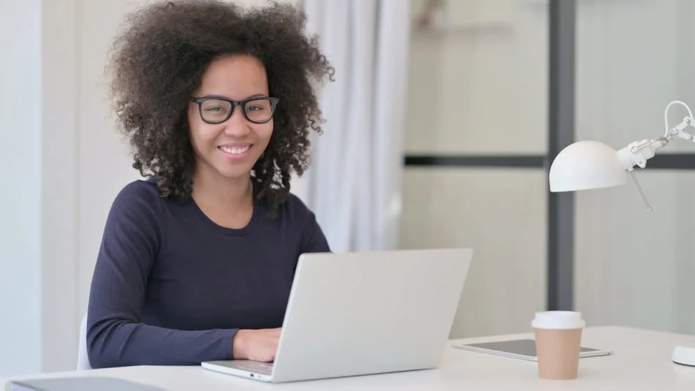 A lady with a layered cut using her Apple MacBook Pro to research how to measure hair lengths.