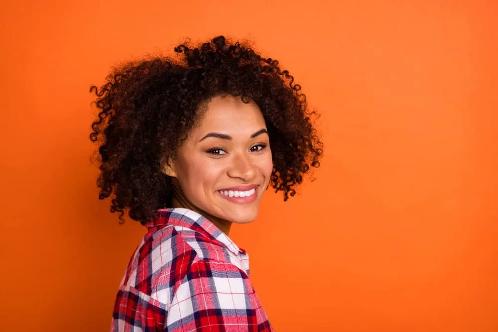 Cute black girl with pure white teeth and a smile wearing jet black curls.