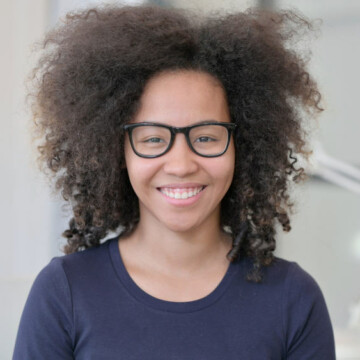 Cute African American female with a voluminous wolf haircut and an oval face shape styled with curl cream.