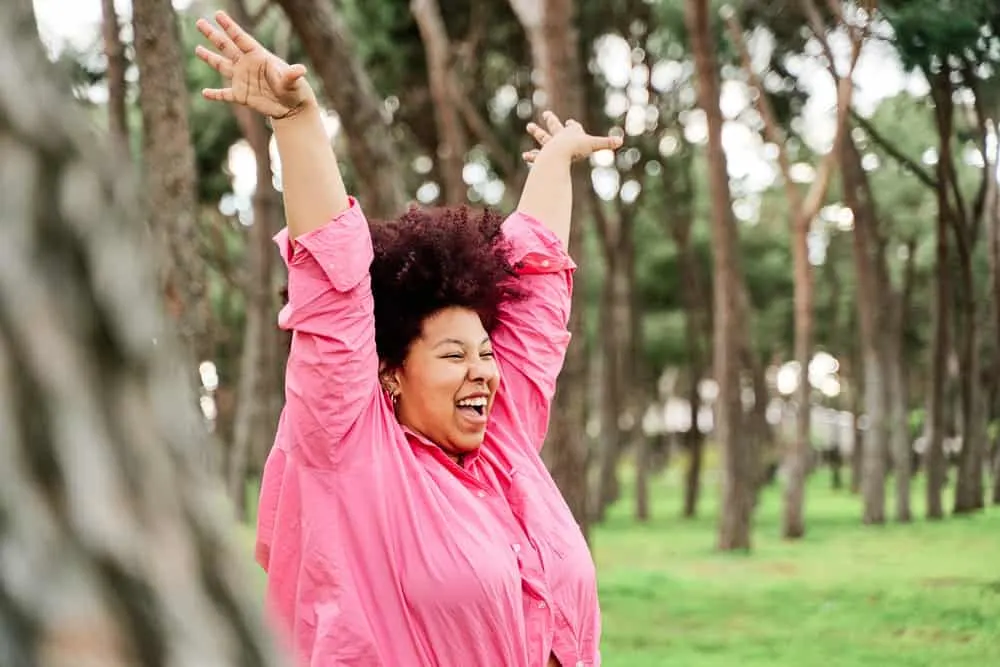 African American female with a curly hair structure taking in the fresh air outdoors.