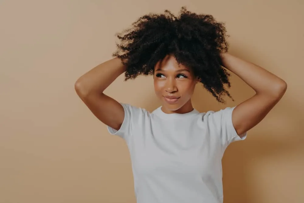 Attractive young woman holding her hair upwards to make her hair curl inward instead of outwards. 