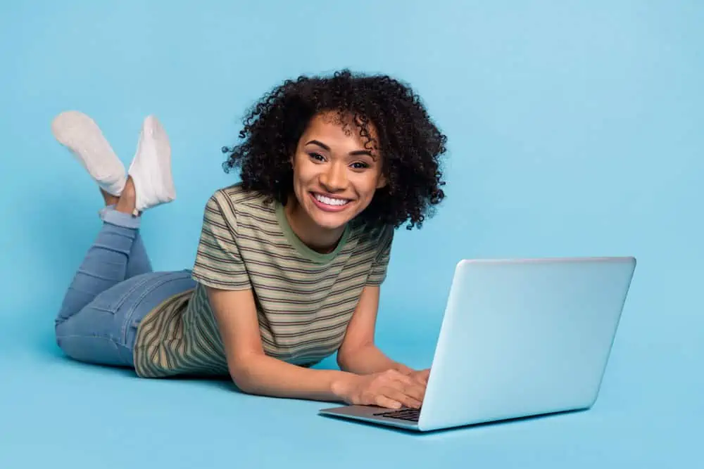 A lady researching hair cuticle damage on her Apple MacBook Pro laptop while laying on the floor.