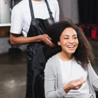 African American female using Regis Salon services to get a shampoo and conditioner service.