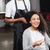 African American female using Regis Salon services to get a shampoo and conditioner service.