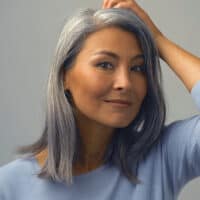 Middle-aged Asian female with natural gray hair follicles that were covered up with permanent hair dye.