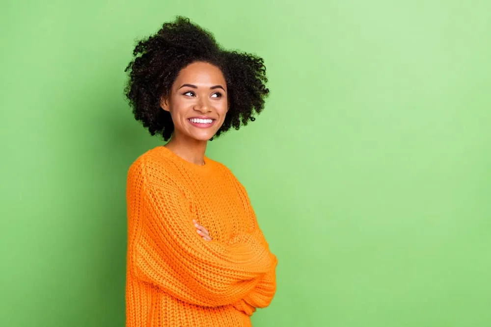 A cute young African American female with curly hair follicles used dark hair dye to cover new gray hair.