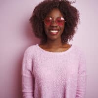 Young African American female covering her own hair with hair weft extensions to create a different hairstyle.