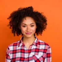 Young black lady with dark brown hair follicles after using a DIY hair coloring kit to dye her hair naturally.