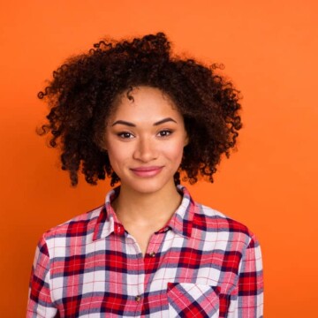 Young black lady with dark brown hair follicles after using a DIY hair coloring kit to dye her hair naturally.