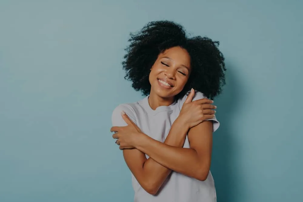 Young African female with loving her curls after using a series of hair masks and deep conditioners.