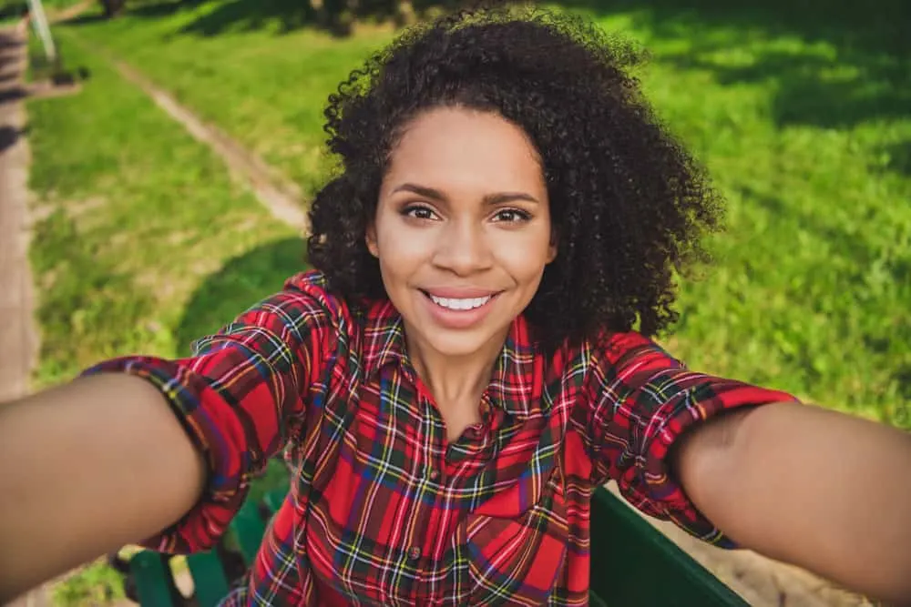 Young black woman wearing a curly shag - a voluminous style perfect for ladies with a 4A hair type.