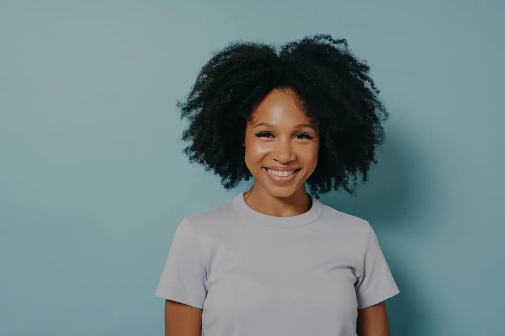 Smiling African American female wearing a wash and go showing how her hair grows outwards. 