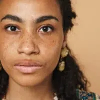 Young African American woman with brassy tones on her dark brown hair after using purple conditioner.