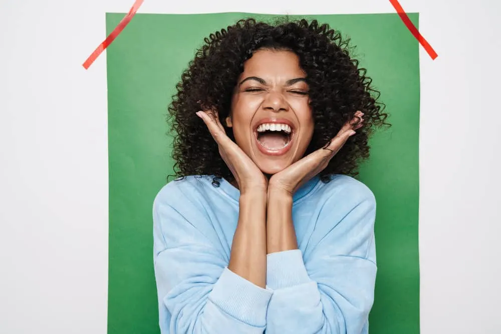 A happy African-American woman after leaving her hair stylist, making her hair feel soft with shampoo and conditioner.