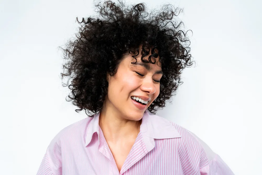 A Latino woman with dark brown oily hair washed with a sulfate-free collagen shampoo without any harsh chemicals.