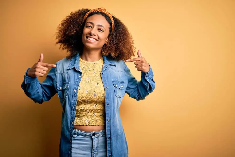 An African American female showing off her new hair dye after using a DIY kit to apply permanent hair color.