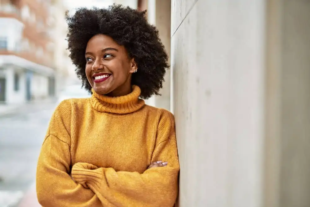 A cute young black woman with dark hair wants to use purple shampoo on her dark brown hair to tone it.