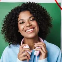 A joyful African American woman with an itchy scalp and white flakes on curly thick hair suffering from hair fall.