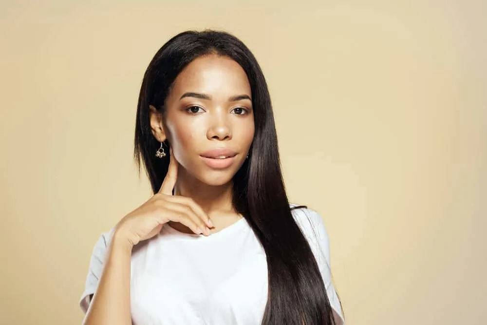 A black female with straightened hair used a heat protectant cream to keep her hair healthy while using a heat tool.