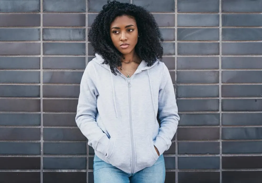 Pretty African American female after drying her wet hair and creating finger curls with her index finger.