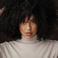 Cute African American woman wearing loose hair with a round brush head and a wide-tooth comb.