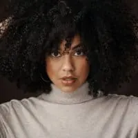 Cute African American woman wearing loose hair with a round brush head and a wide-tooth comb.