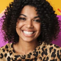 Cute young African American female with color-treated hair suffering from an itchy scalp due to dandruff.