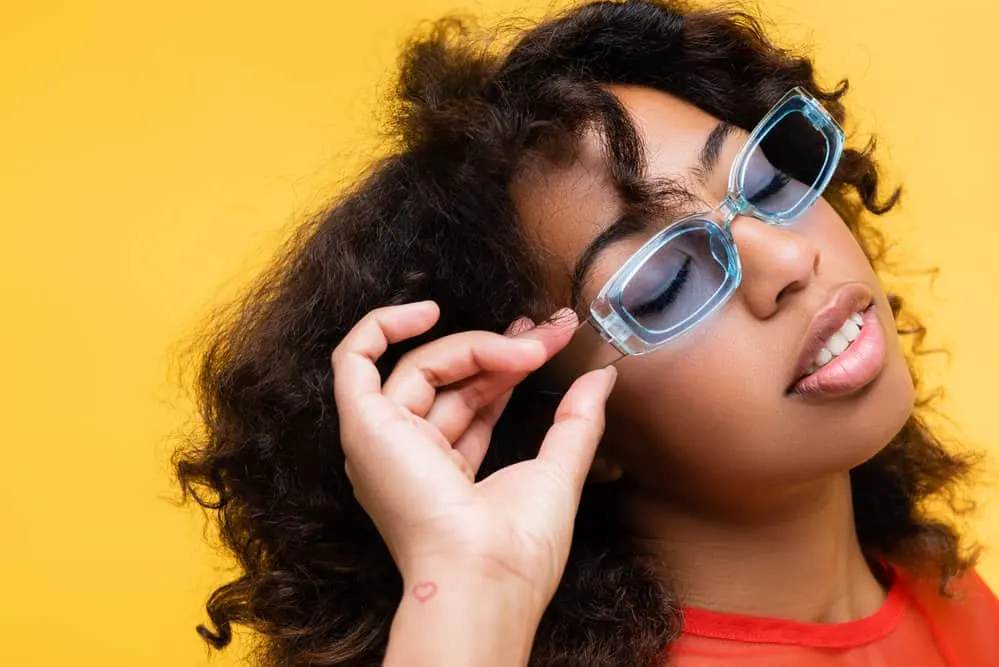 A cute black woman with medium-hair length, after using a hair dryer on damp black female hair, has frizzy hair.