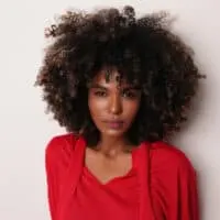 African American woman with a big curly hairdo with an amazing smell that triggers pleasure while brushing past.