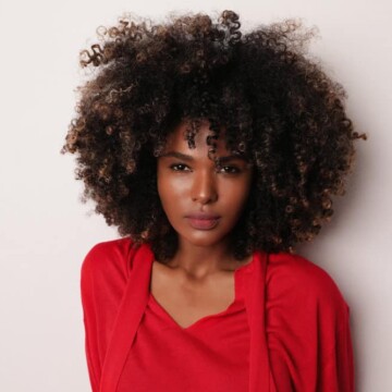 African American woman with a big curly hairdo with an amazing smell that triggers pleasure while brushing past.