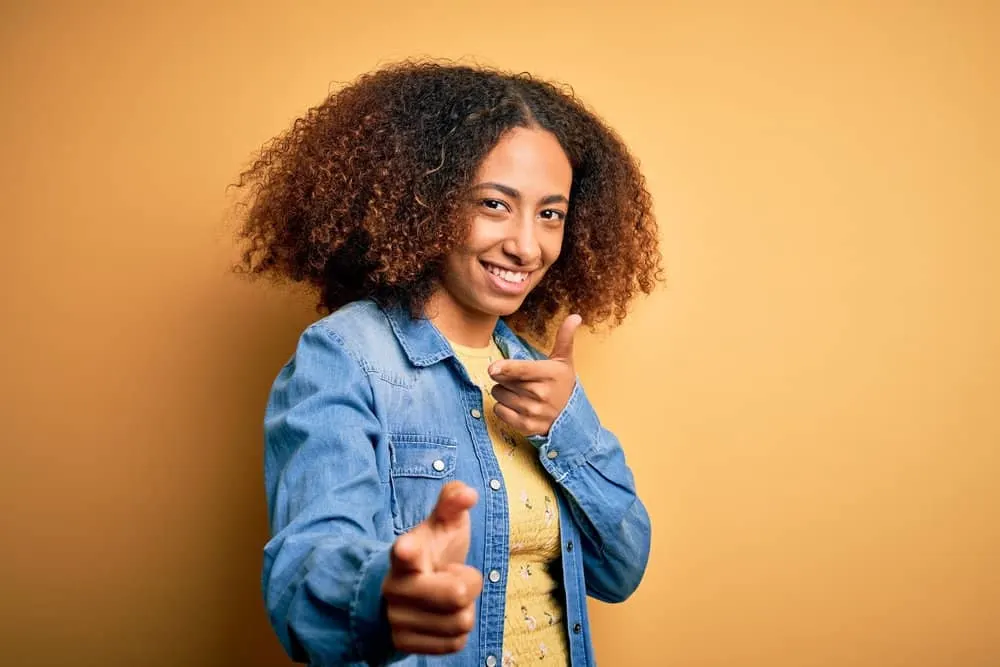 A black girl with permanent hair color pigments on curly strands with a very soft texture styled with natural oils.