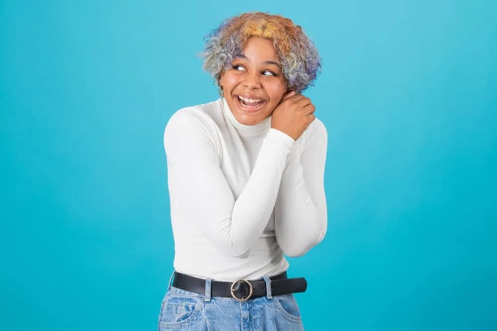 A happy young black female that has been using heat styling tools on her hair everyday on her 3B natural hair type.