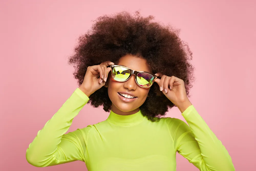 A young African woman with medium-dense hair wearing a curly hairstyle was sprayed with texture spray.