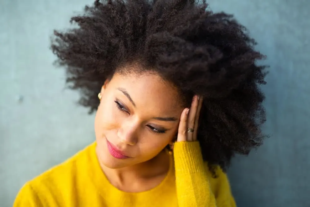 A black woman wearing an afro with multiple curl patterns that's been treated with a deep conditioner.