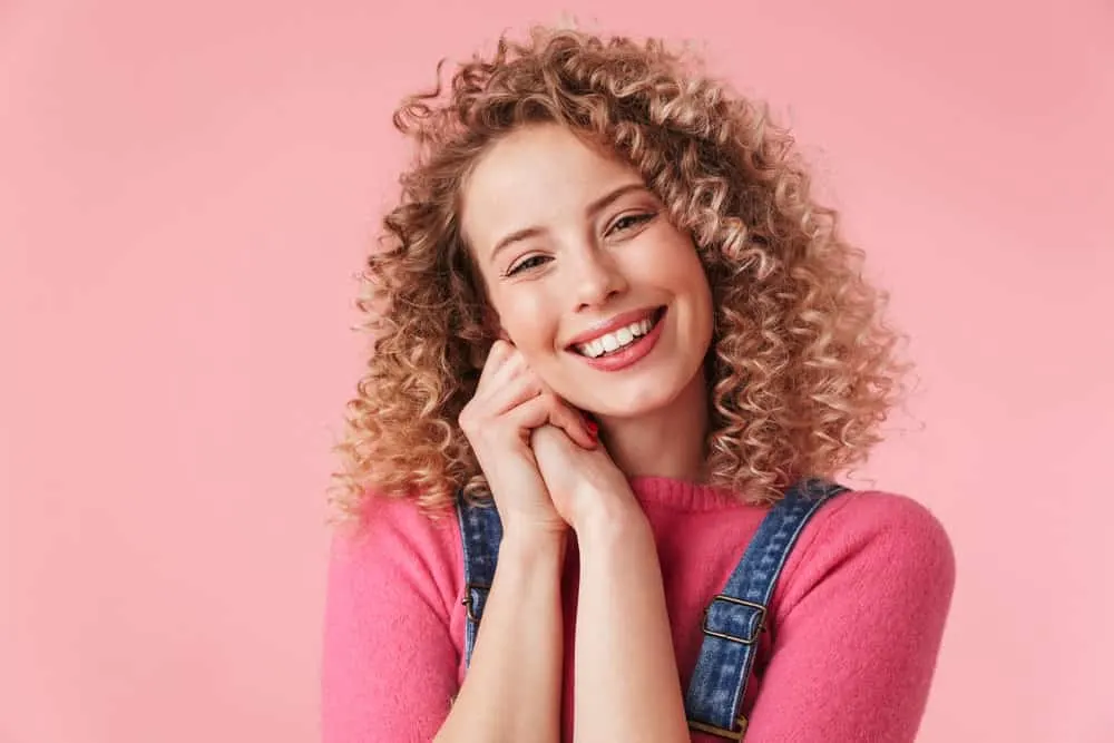 A cheerful young female with a dark natural hair color just had a natural lightening technique at her local hair salon.