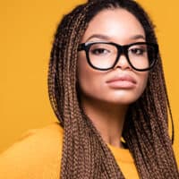 Light-skinned black girl with a pear face shape and a high forehead wearing brown braids on black straight hair.