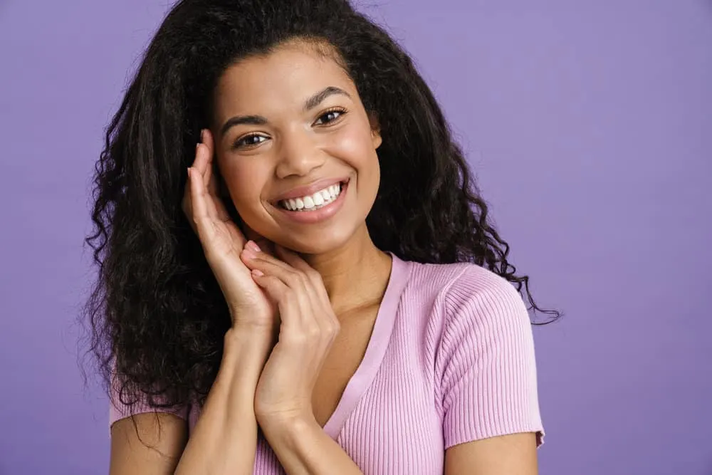 African woman after using hair dye to cover gray regrowth on her natural 3B black hair strands.