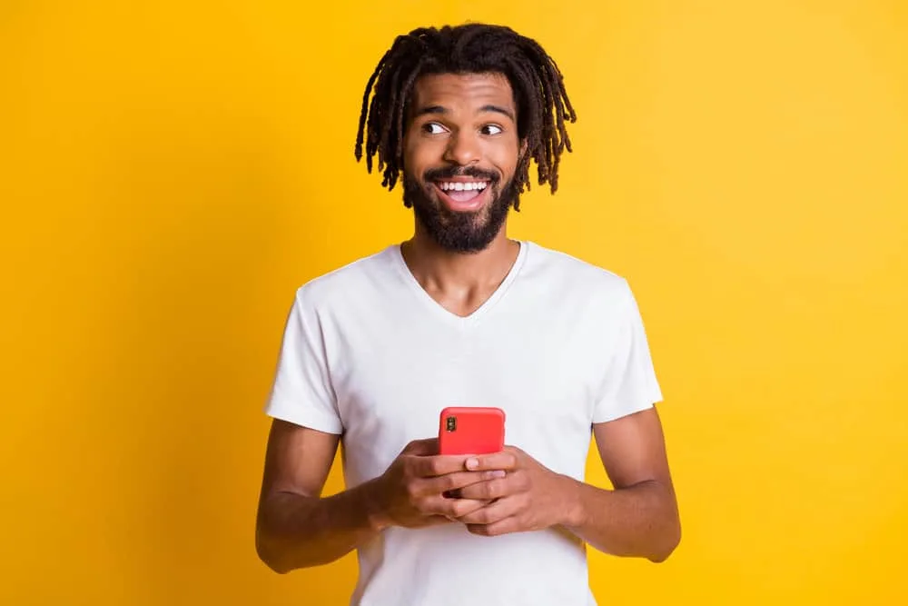 A black guy watching YouTube videos of loc styles worn by popular rappers and R&B artists, like Polo G.